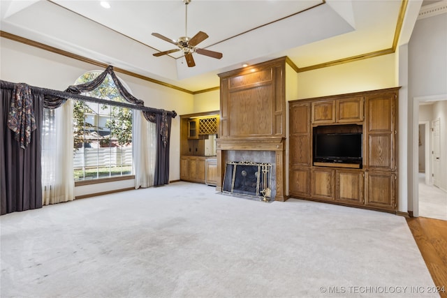 unfurnished living room with a raised ceiling, crown molding, light hardwood / wood-style flooring, ceiling fan, and a fireplace