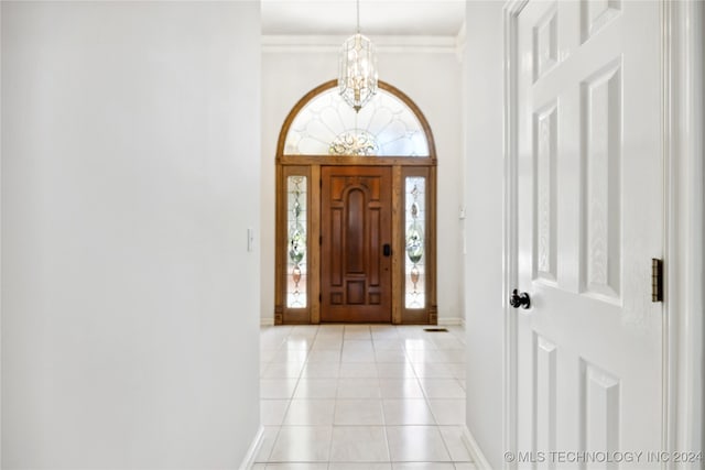 entryway featuring light tile patterned floors, crown molding, and a chandelier