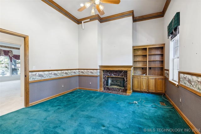 unfurnished living room featuring ceiling fan, a high end fireplace, dark carpet, and ornamental molding