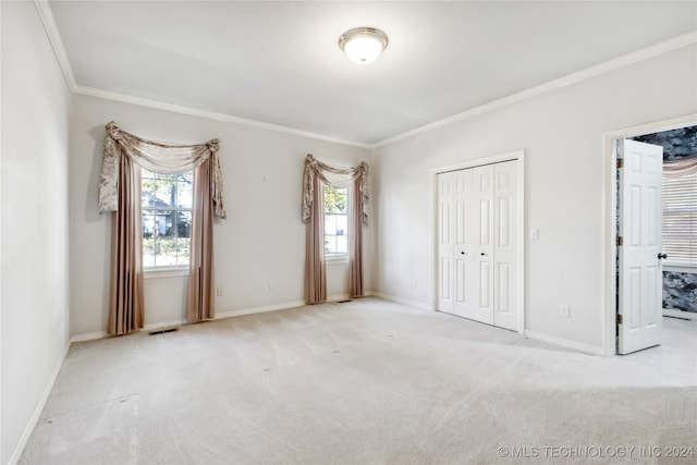 unfurnished bedroom featuring light colored carpet, ornamental molding, and a closet