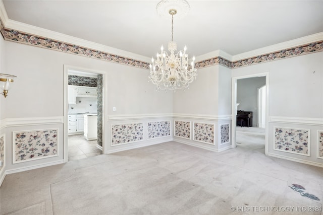 spare room featuring crown molding, light carpet, and a chandelier