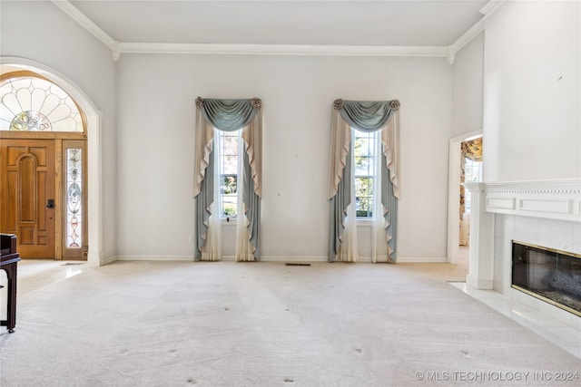 carpeted foyer entrance featuring ornamental molding and a tiled fireplace