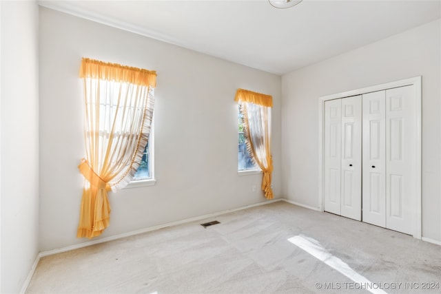 unfurnished bedroom with a closet and light colored carpet