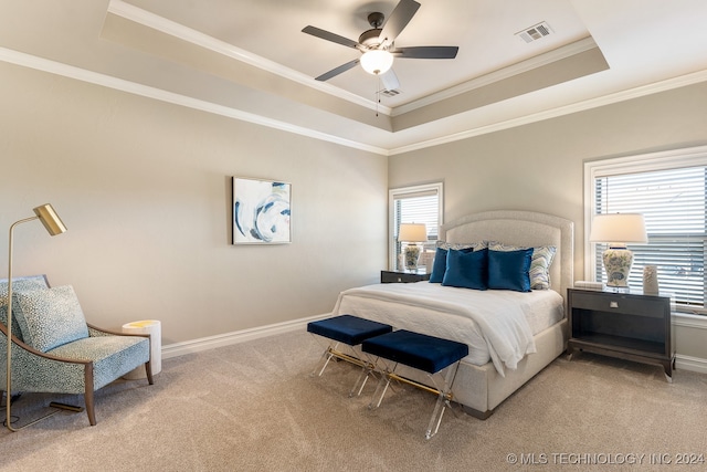 carpeted bedroom with a raised ceiling, multiple windows, ceiling fan, and crown molding