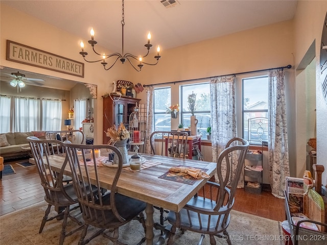 dining space featuring hardwood / wood-style floors, ceiling fan with notable chandelier, and vaulted ceiling