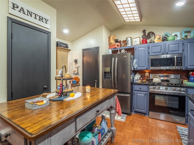 kitchen featuring appliances with stainless steel finishes, light hardwood / wood-style floors, blue cabinets, and lofted ceiling