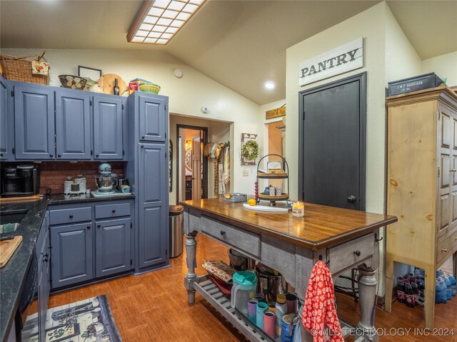 kitchen with black dishwasher, light hardwood / wood-style floors, lofted ceiling, and blue cabinets