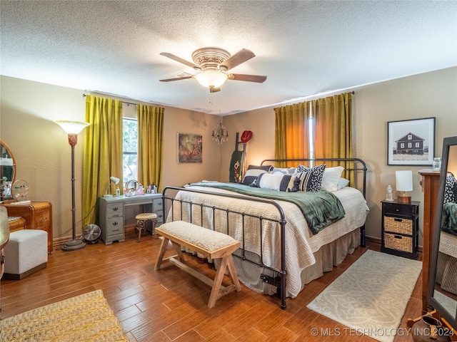 bedroom with a textured ceiling, hardwood / wood-style flooring, and ceiling fan