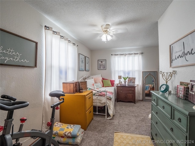 bedroom featuring a textured ceiling, light colored carpet, and ceiling fan