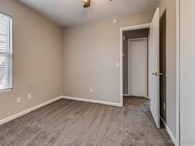 unfurnished bedroom featuring a textured ceiling, carpet floors, and ceiling fan