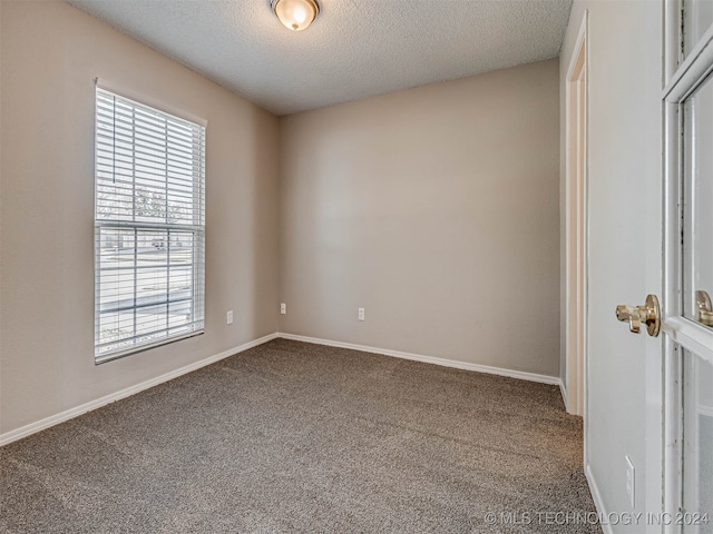 carpeted spare room with a textured ceiling