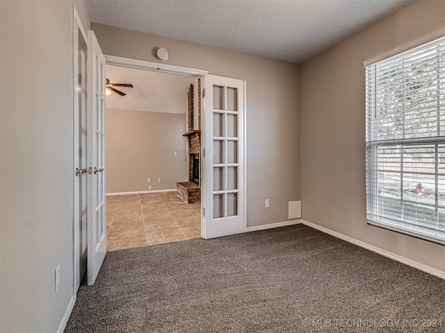 spare room featuring a textured ceiling, ceiling fan, light carpet, and french doors