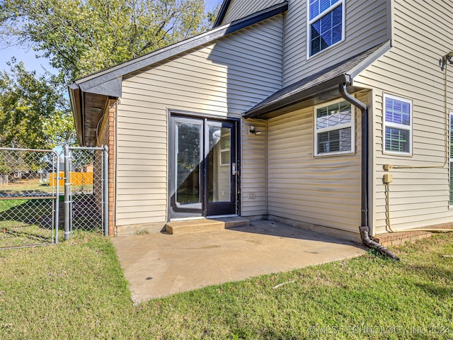 view of exterior entry with a yard and a patio