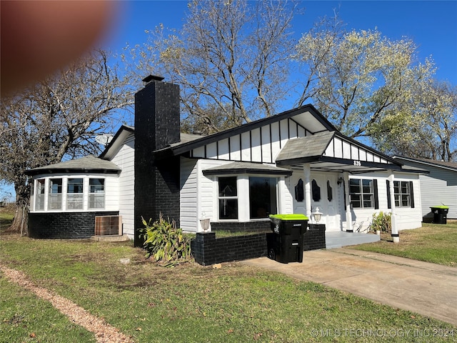 view of front of home with brick siding, a chimney, board and batten siding, and a front yard