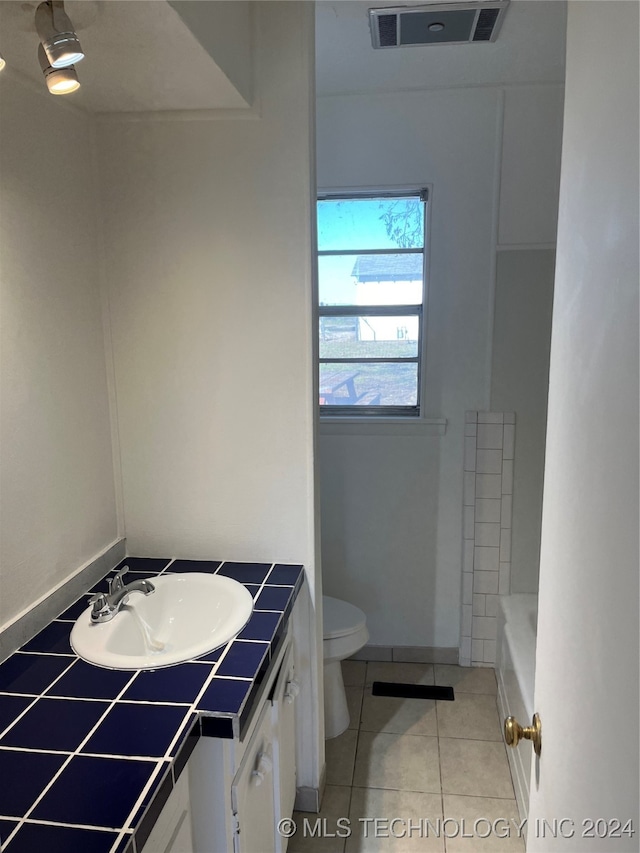 bathroom with toilet, vanity, tile patterned floors, and a washtub