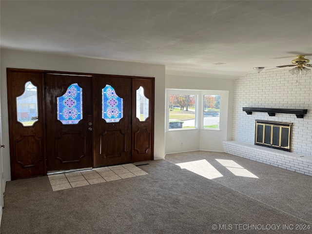 carpeted entrance foyer featuring a ceiling fan and a fireplace