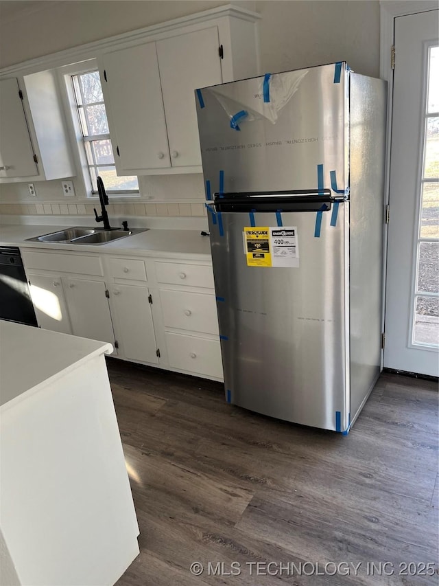 kitchen featuring dishwasher, white cabinets, a sink, and freestanding refrigerator