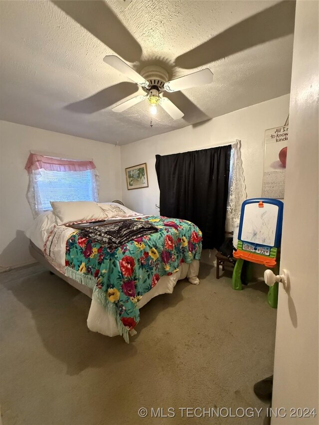 bedroom with ceiling fan, carpet, and a textured ceiling