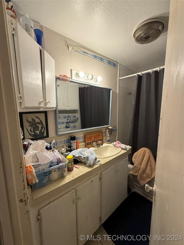 bathroom with curtained shower, vanity, and a textured ceiling