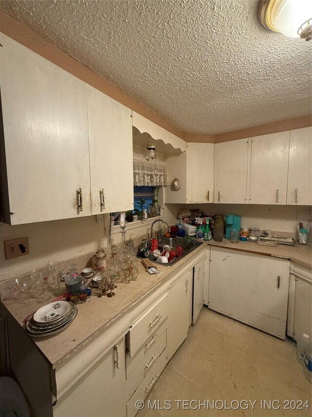 kitchen featuring a textured ceiling, white cabinetry, and sink