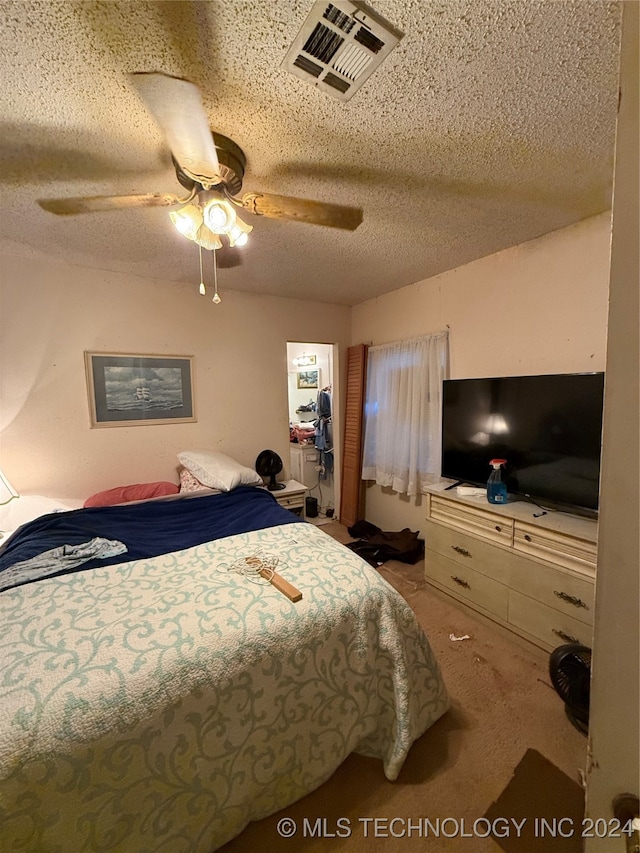 bedroom featuring ceiling fan, carpet floors, and a textured ceiling