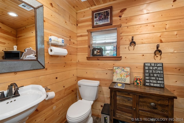 bathroom with wood walls, sink, and toilet