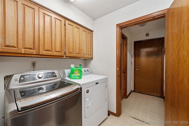 washroom featuring cabinets, a textured ceiling, and washing machine and dryer