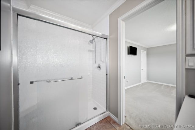 bathroom with tile patterned floors, a shower with door, and ornamental molding