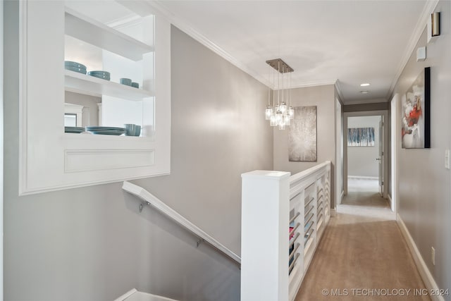 hallway featuring light carpet, crown molding, and a notable chandelier