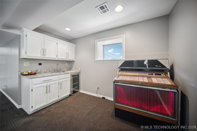 kitchen featuring dark colored carpet, white cabinetry, sink, and wine cooler