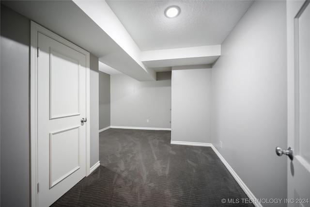 basement with dark carpet and a textured ceiling