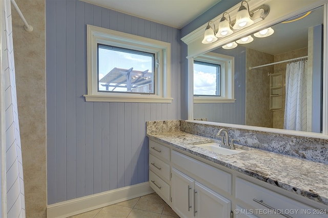 bathroom with tile patterned floors, vanity, walk in shower, and wooden walls