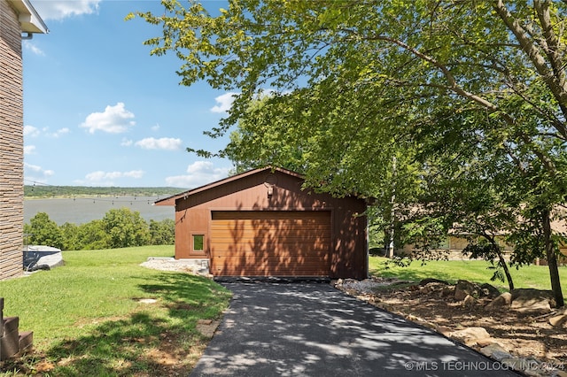 view of property exterior featuring a garage, a yard, and an outbuilding