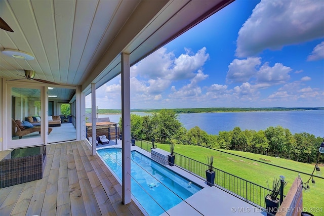 view of pool with outdoor lounge area, a water view, a yard, and a patio