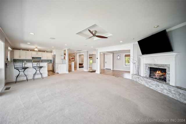 unfurnished living room featuring ceiling fan, ornamental molding, a fireplace, and light hardwood / wood-style flooring