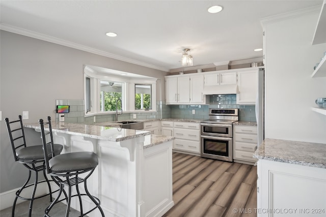 kitchen with crown molding, range with two ovens, white cabinetry, and kitchen peninsula