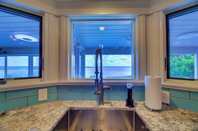 room details featuring light stone counters, crown molding, sink, and green cabinetry