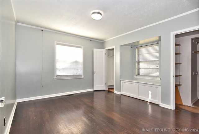 unfurnished bedroom featuring a textured ceiling, multiple windows, dark hardwood / wood-style floors, and ornamental molding