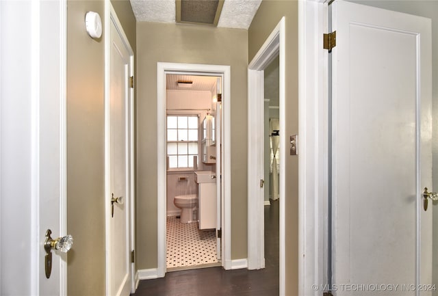 corridor with a textured ceiling and dark hardwood / wood-style flooring