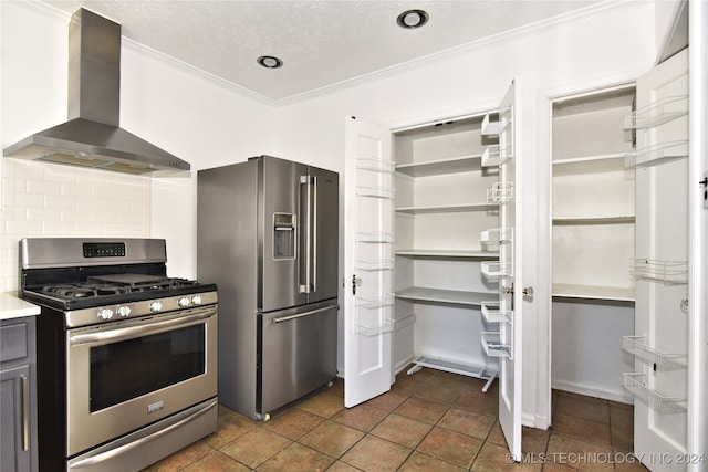 kitchen with appliances with stainless steel finishes, backsplash, dark tile patterned floors, crown molding, and wall chimney range hood