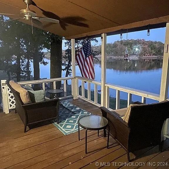 deck with a water view and ceiling fan