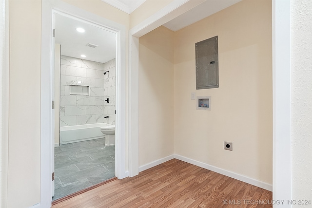 bathroom featuring hardwood / wood-style floors, tiled shower / bath combo, electric panel, and toilet