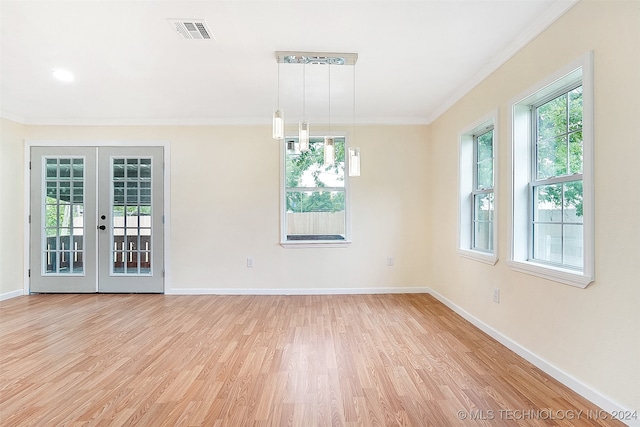 empty room with a healthy amount of sunlight, light hardwood / wood-style floors, crown molding, and french doors