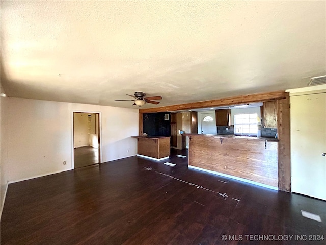 unfurnished living room featuring a textured ceiling, ceiling fan, and dark wood-type flooring