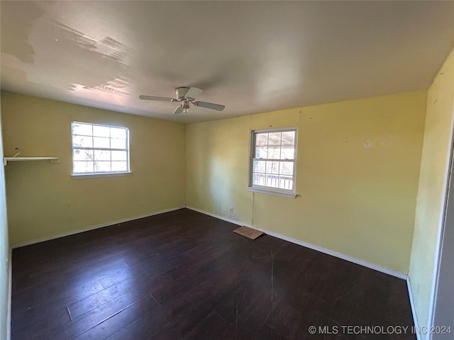 empty room with a wealth of natural light, ceiling fan, and dark hardwood / wood-style floors