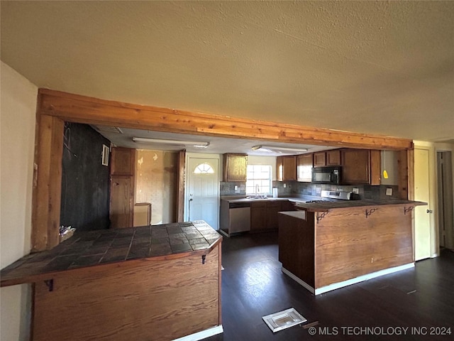 kitchen with dark wood-type flooring, tasteful backsplash, stainless steel dishwasher, kitchen peninsula, and a breakfast bar area