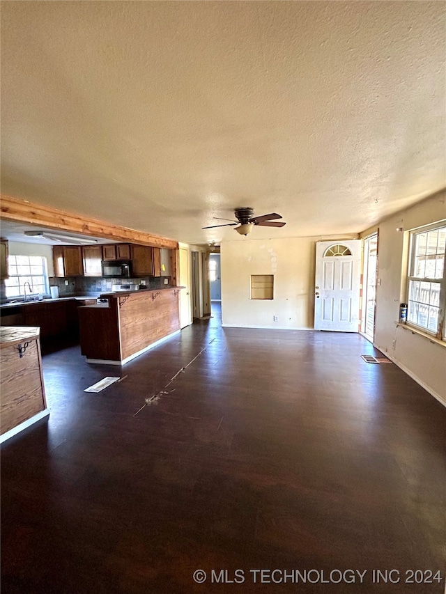 unfurnished living room featuring a textured ceiling, ceiling fan, and sink