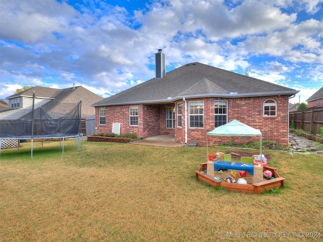 rear view of house with a lawn, a patio area, and a trampoline