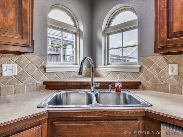 kitchen with stainless steel dishwasher, decorative backsplash, and sink