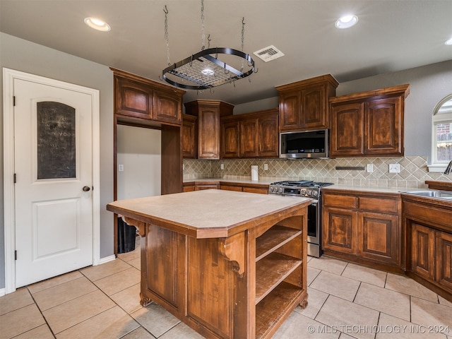 kitchen with tasteful backsplash, a kitchen island, light tile patterned flooring, and appliances with stainless steel finishes